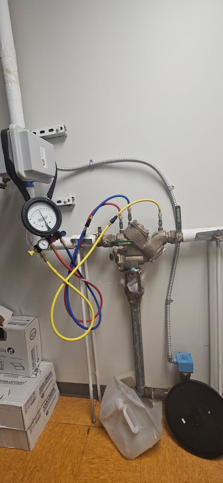 Backflow test gauge kit connected to a commercial backflow assembly indoors