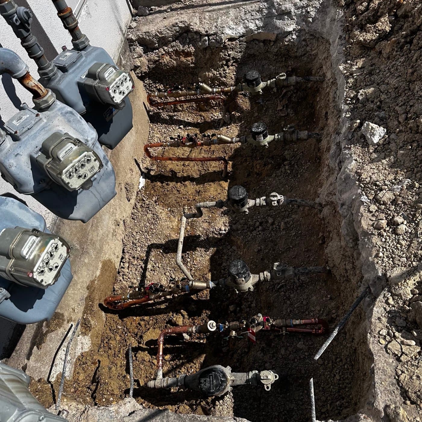 A row of separate meters and backflow assemblies serviced across one multi-property job