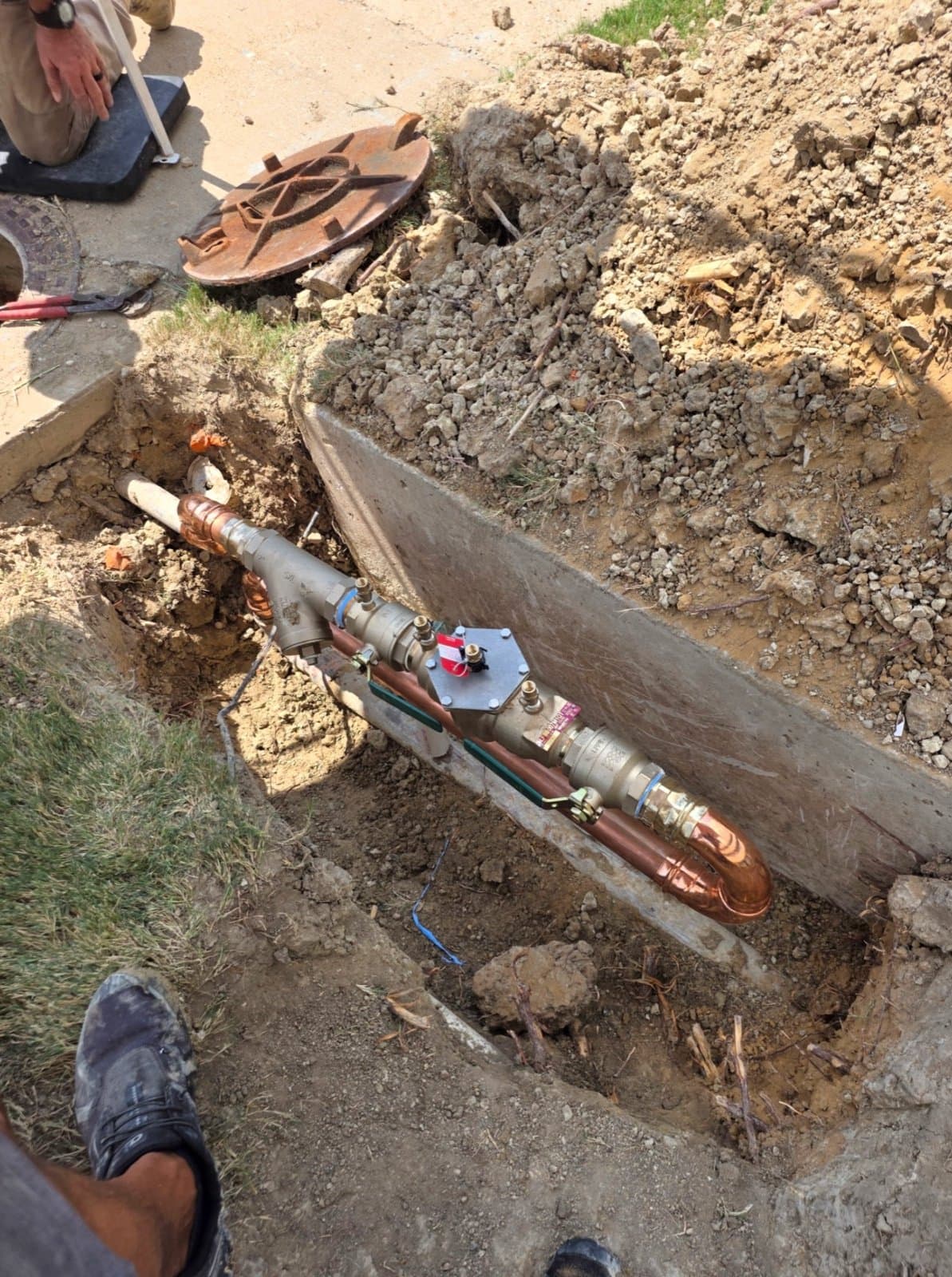 Larry's Plumbing installing a new commercial backflow assembly in an excavated trench