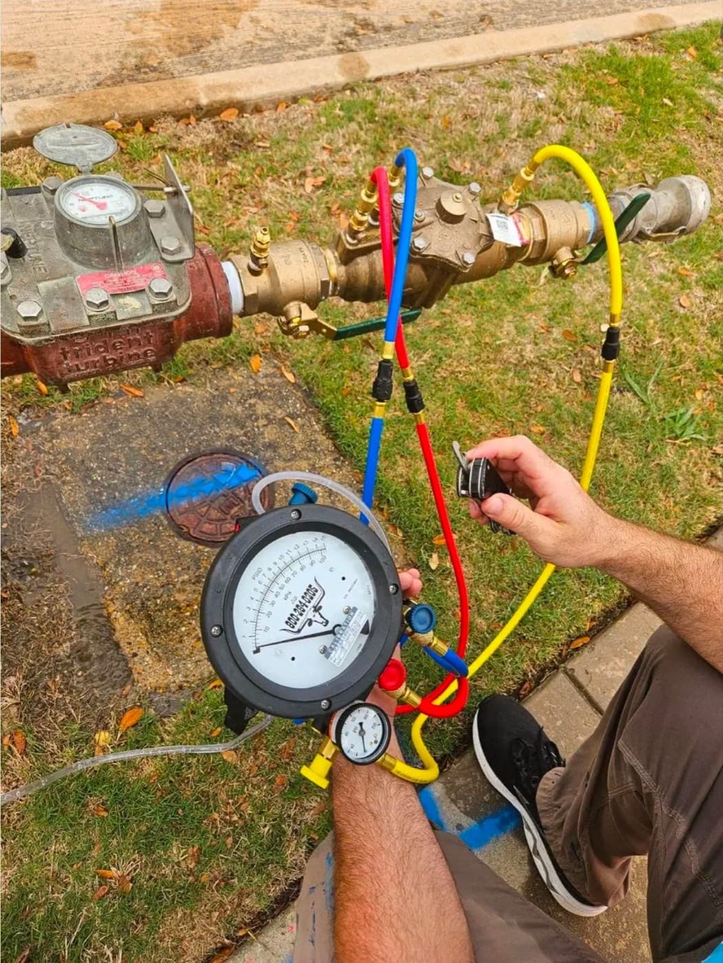 Larry's Plumbing technician reading a backflow test gauge on a commercial double check assembly